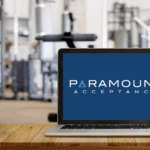 Computer at a gym front desk showing the Paramount Acceptance logo, representing fitness software for gyms