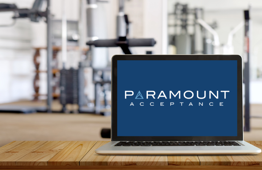 Computer at a gym front desk showing the Paramount Acceptance logo, representing fitness software for gyms